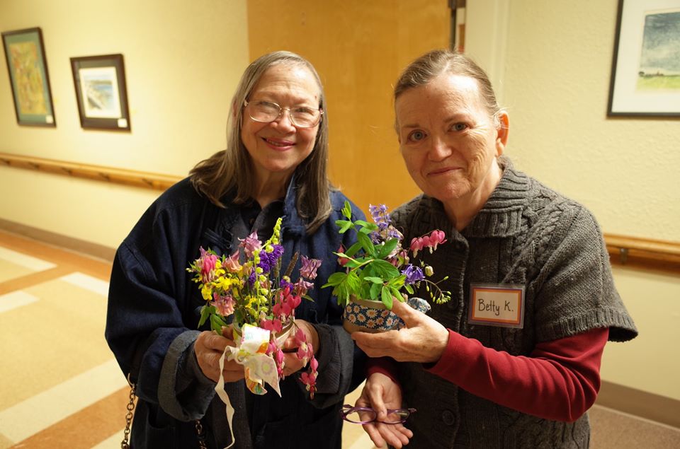 Two Grace Center participants showing off their bouquets they made in a flower arranging activity