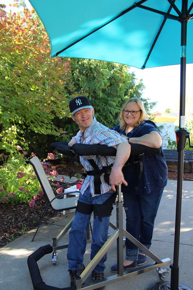 A Grace Center participant using the ambulator with the assistant of a nurse